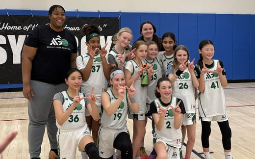 Girls basketball team smiling with their coach