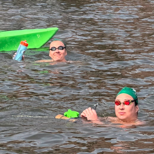 Two AGUA Masters swimmers in the water smiling to camera