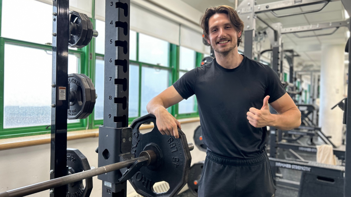 Asphalt Green fitness trainer posing next to the squat rack machine