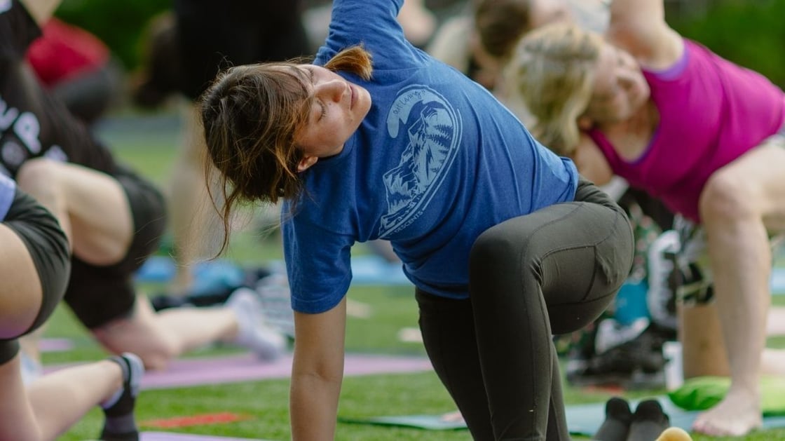 A person practicing yoga in an outdoor group exercise class.