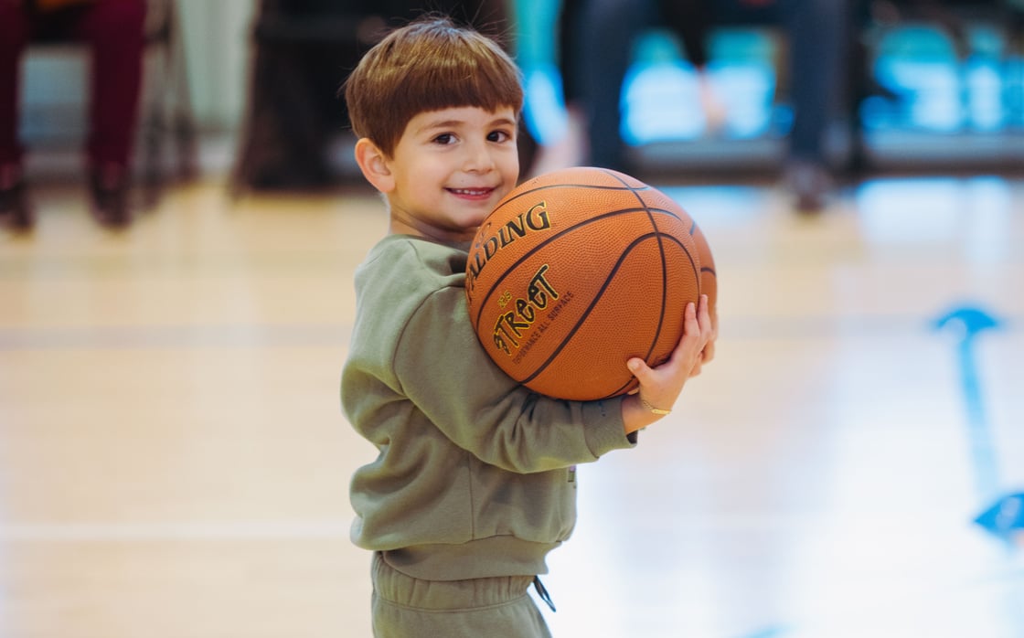 Toddler holding two basketballs smiling to camera