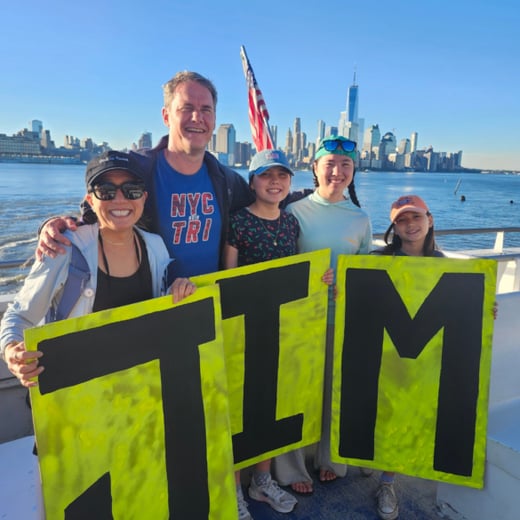 Four people holding signs with the letters J, I, and M.